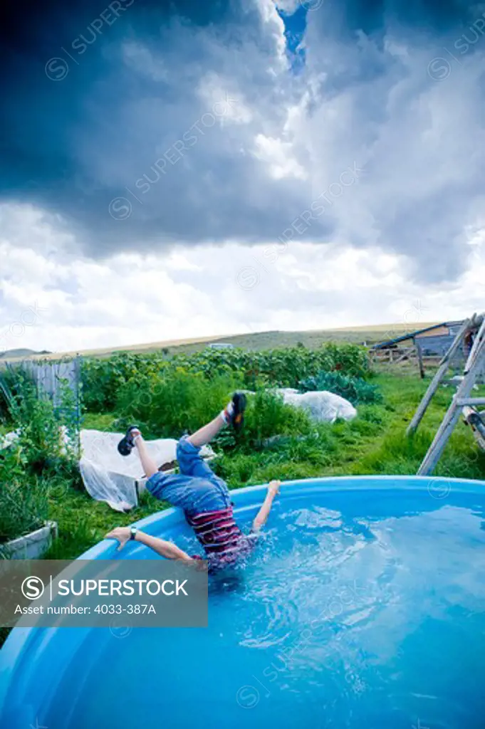 Boy sticking his head in a backyard pool, Bozeman, Montana, USA