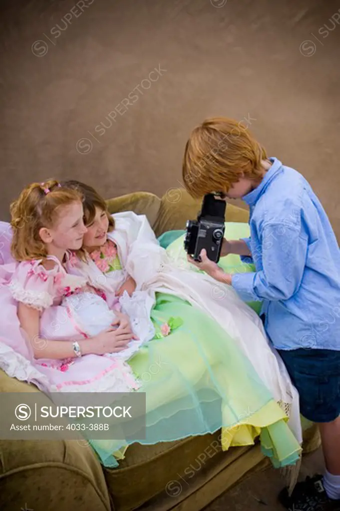 Boy taking a picture of two girls in fancy dresses, San Diego, California, USA