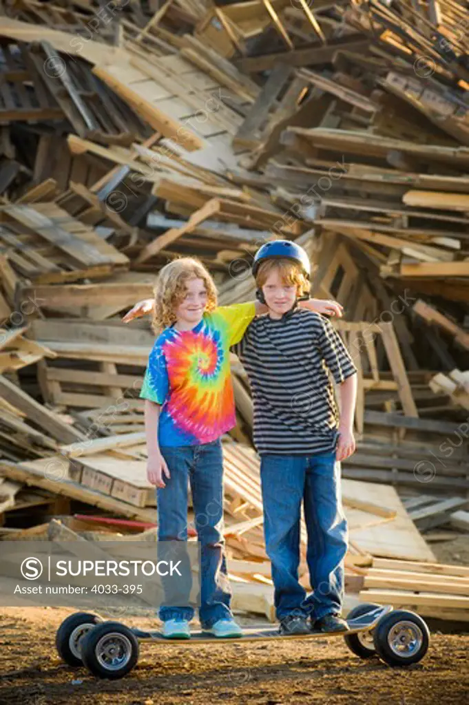 Two boys standing in front of a heap of recyclable wooden products