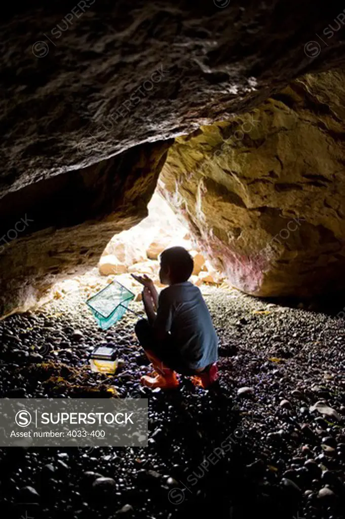 Boy holding a butterfly net in a sea cave