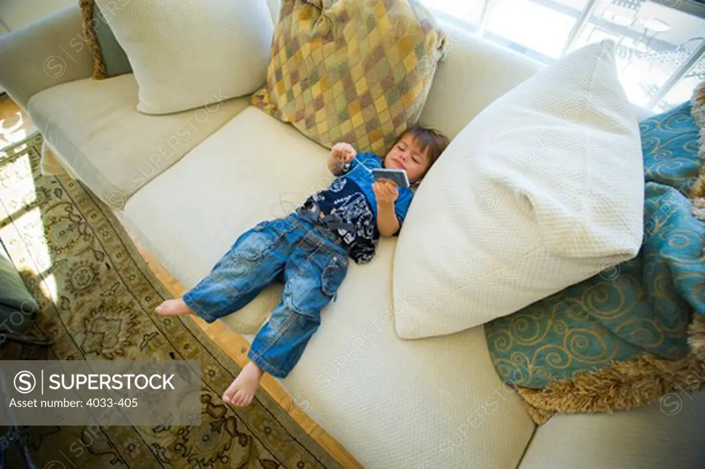 High angle view of a boy listening to mp3 player on a couch