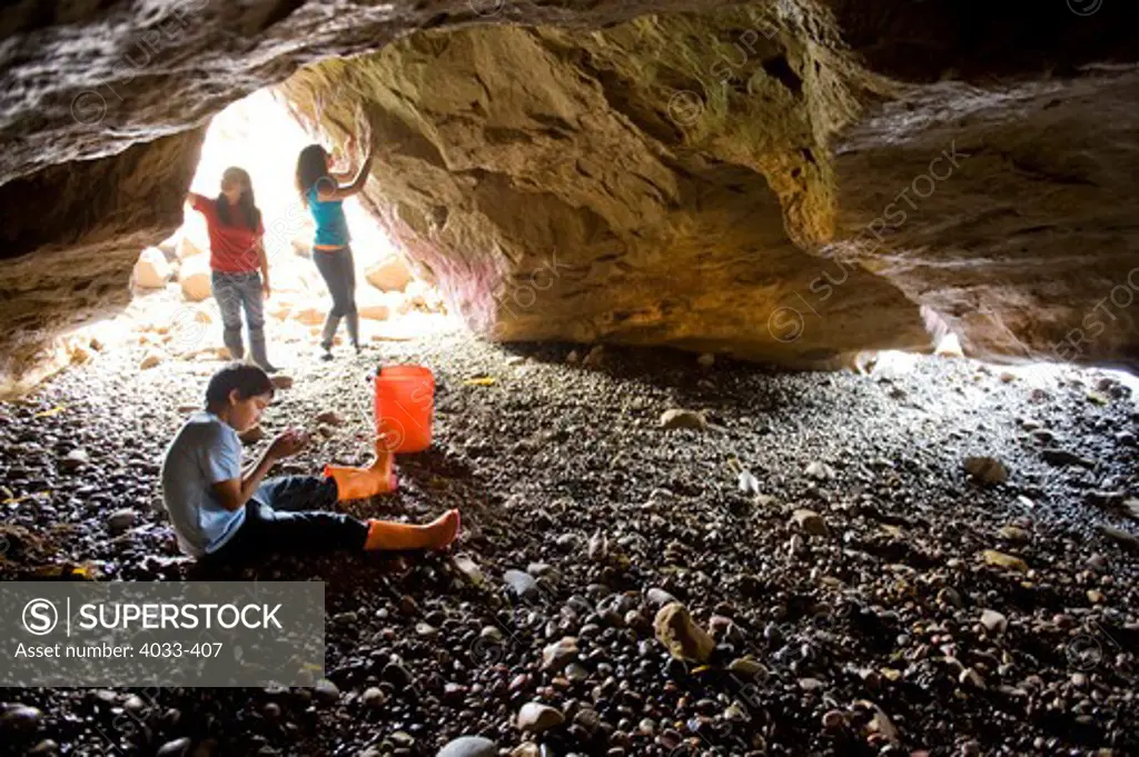 Three children looking around in a sea cave