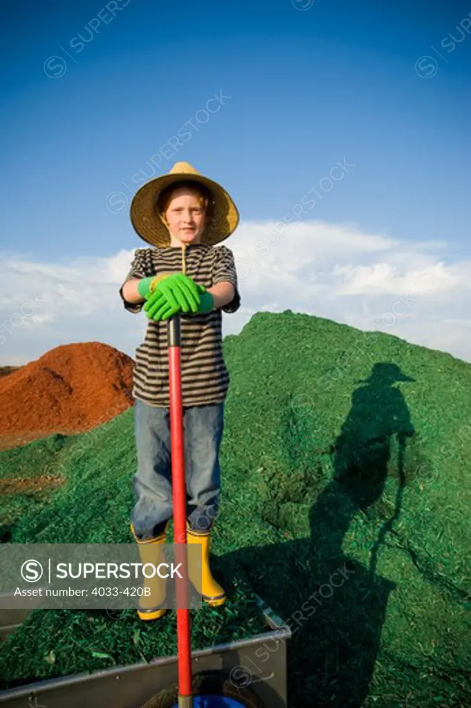 Boy with a shovel in front of a heap of dyed wood chips