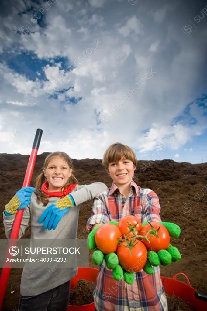 Girl standing with a boy holding tomatoes