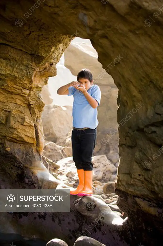 Boy standing at the entrance of a sea cave