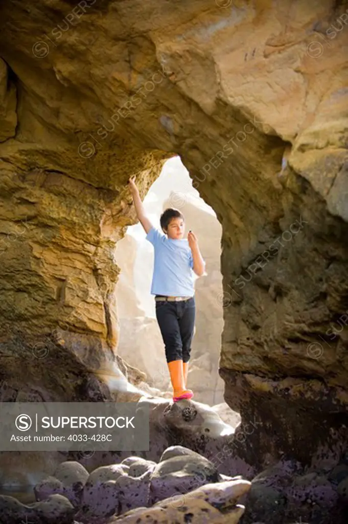 Boy standing at the entrance of a sea cave
