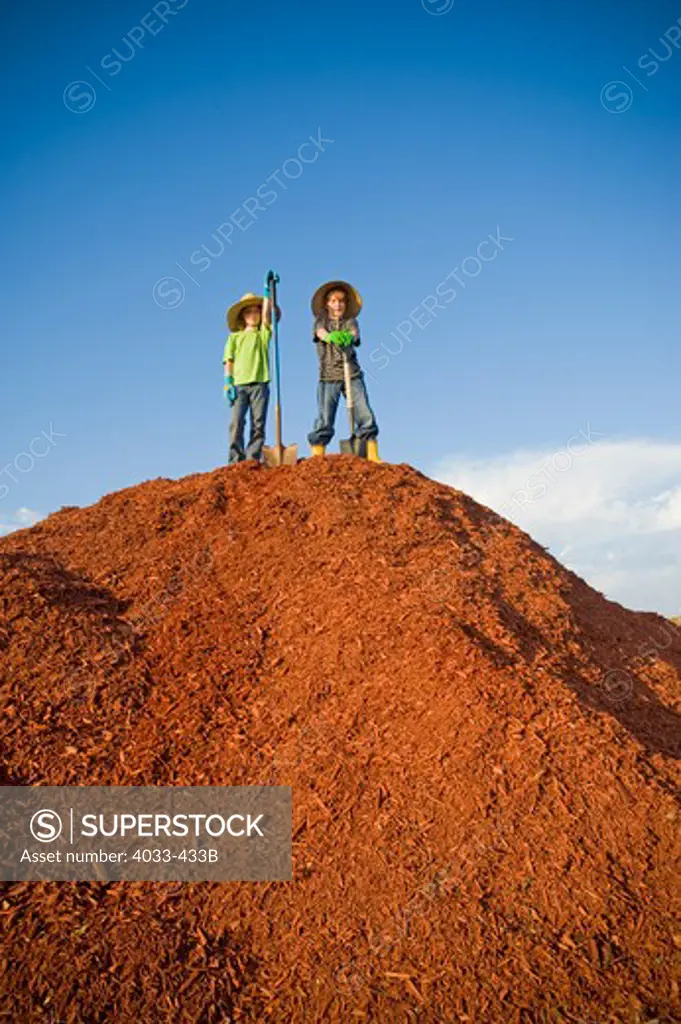Boy and a girl standing on a heap of dyed wood chips