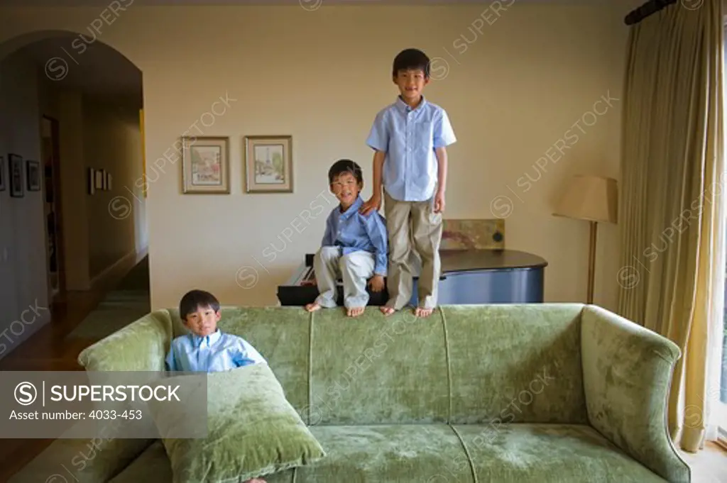 Three boys playing on a couch