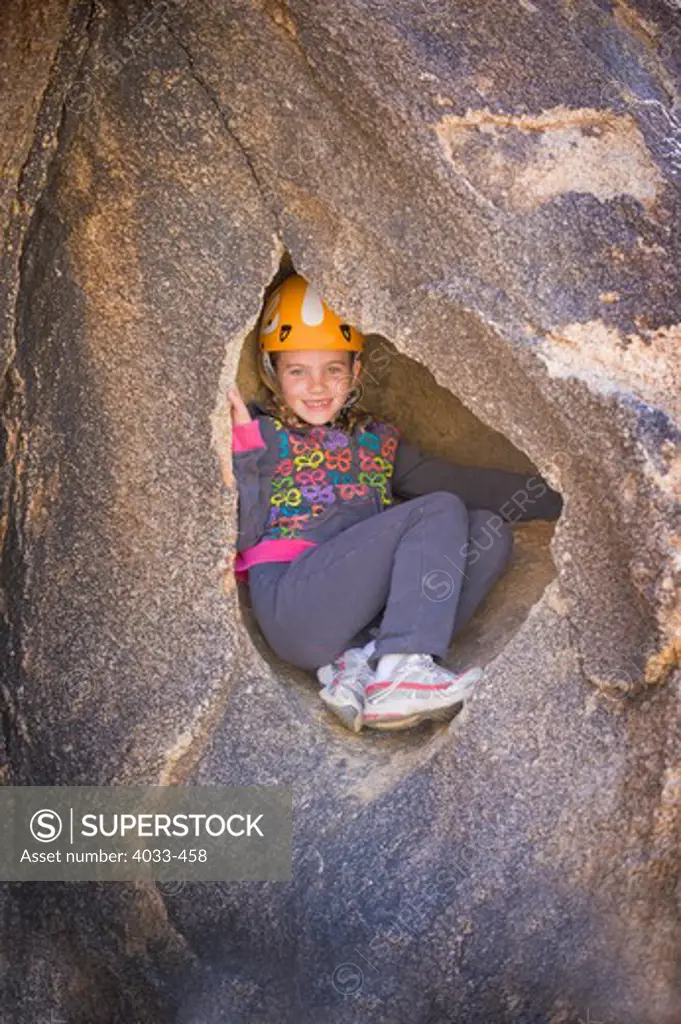 Girl sitting in a small cave, Joshua Tree National Monument, California, USA