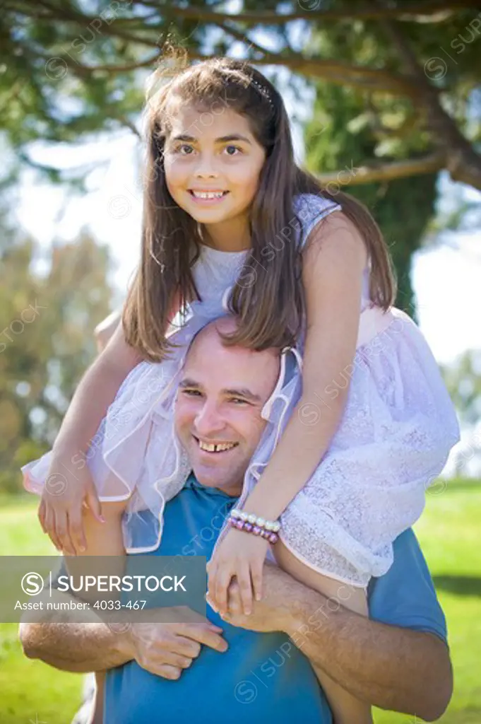 Mature man carrying his daughter in a park