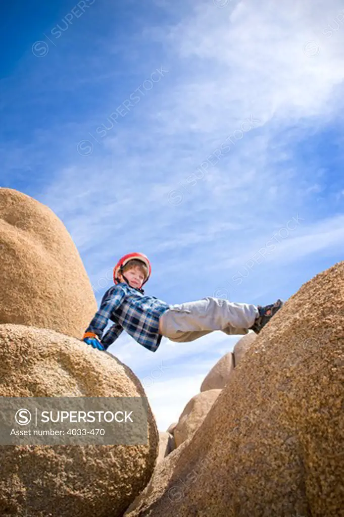 Boy straddling boulders, Joshua Tree National Monument, California, USA