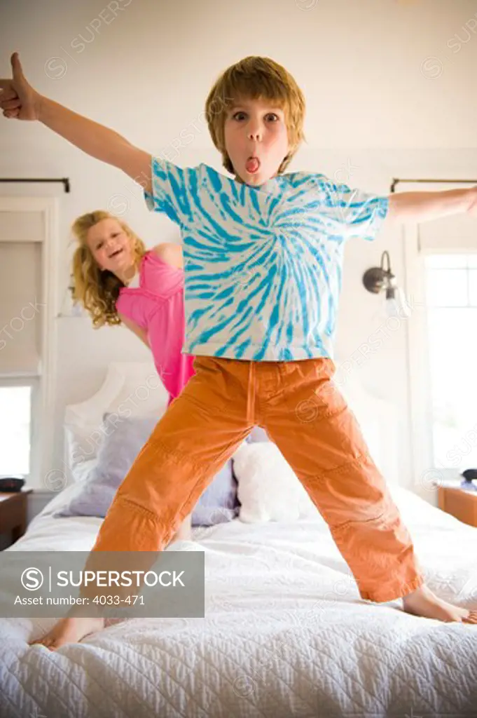 Boy playing on the bed with his sister