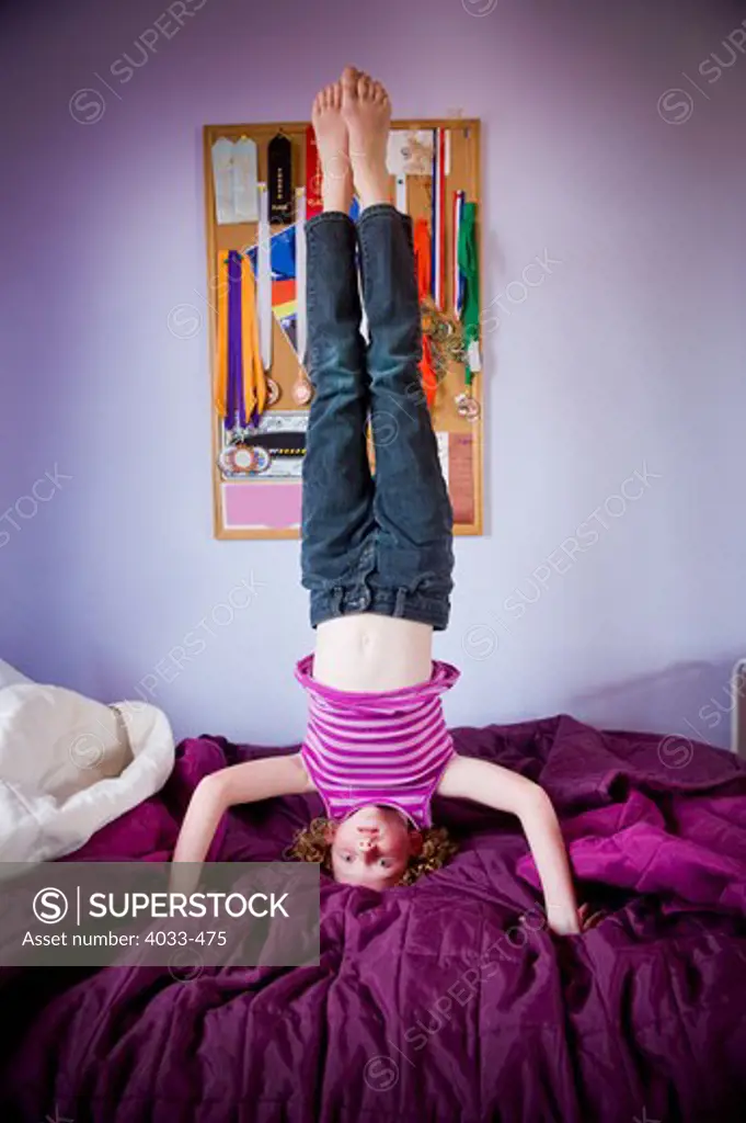 Girl doing headstand on the bed