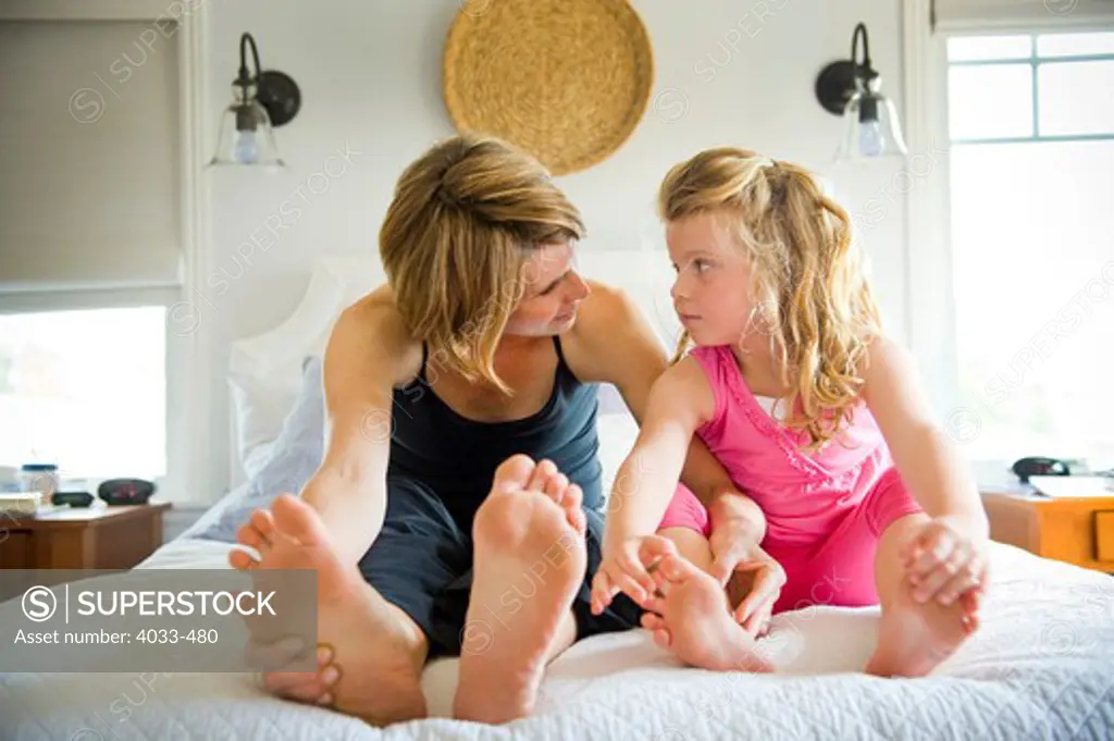 Young woman sitting with her daughter on the bed