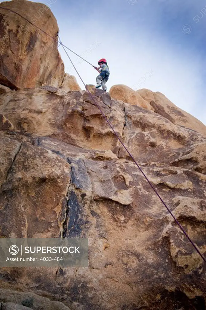 Boy rock climbing, Joshua Tree National Monument, California, USA
