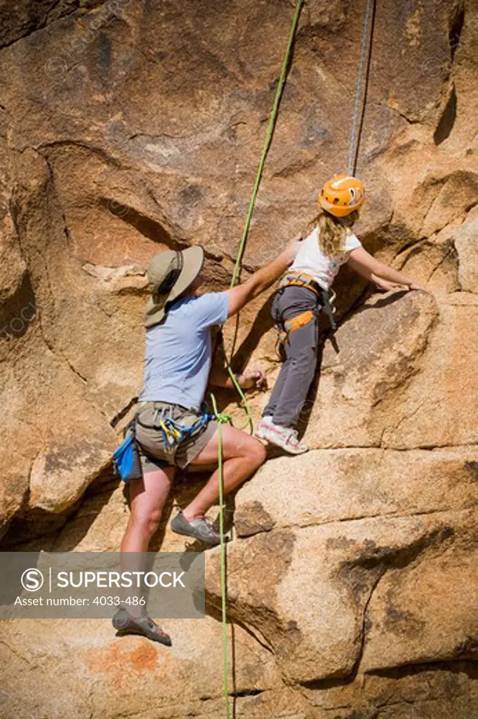 Mid adult man helping his daughter to climb a rock, Joshua Tree National Monument, California, USA