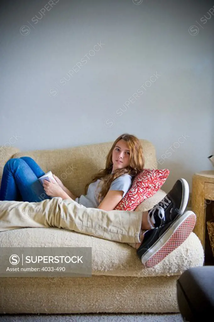 Teenage girl reading a book on a couch