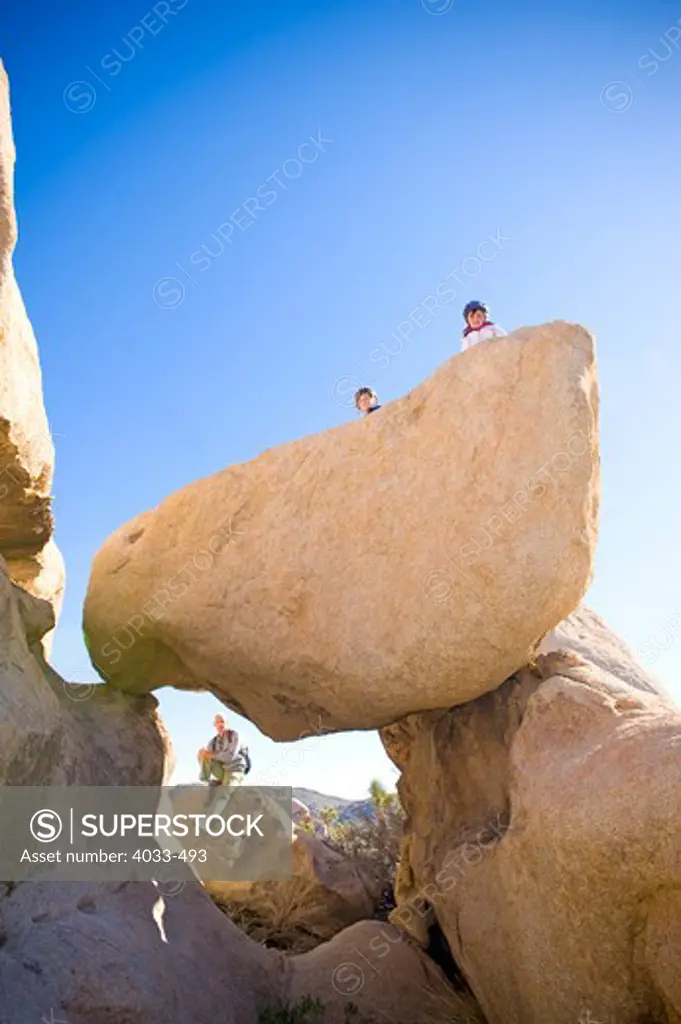 Man with his two children on rocks, Joshua Tree National Monument, California, USA