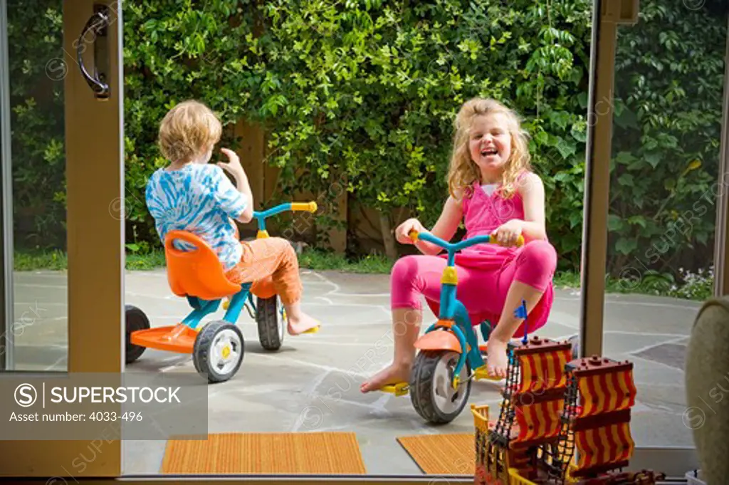 Boy and his sister riding tricycles
