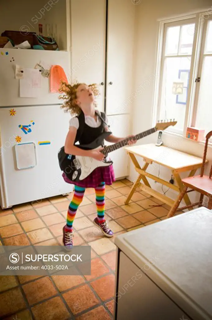 Girl playing an electric guitar in a kitchen