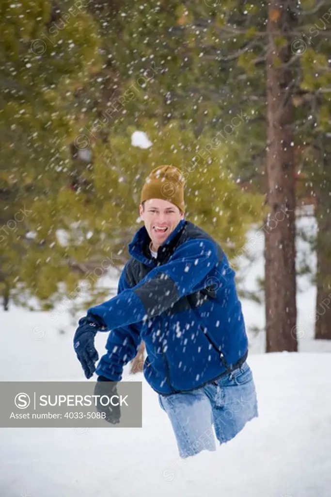 Mid adult man throwing snowballs