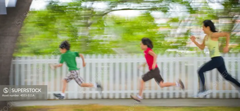 Mid adult woman running with her children in a park