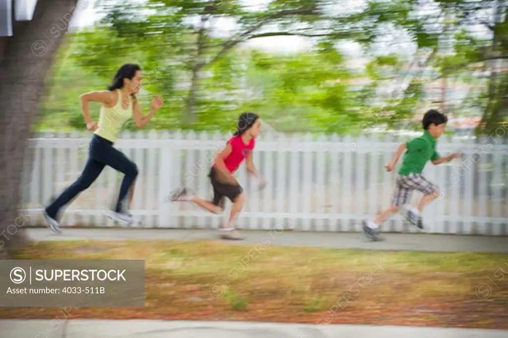 Mid adult woman running with her children in a park