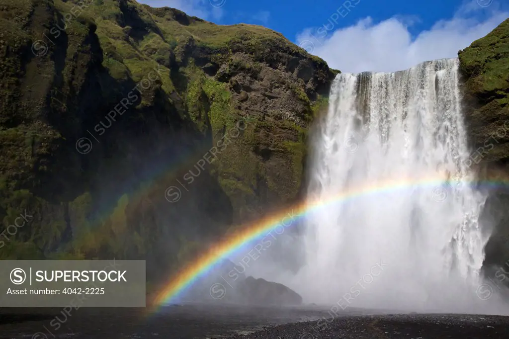 Iceland, Skogafoss waterfall with rainbow in summer sunshine
