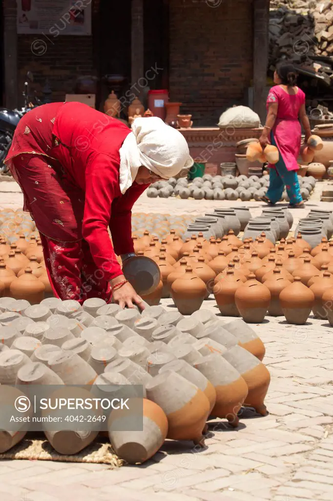 Woman turning pots to dry in sunshine, Potter's Square, Bhaktapur, Nepal