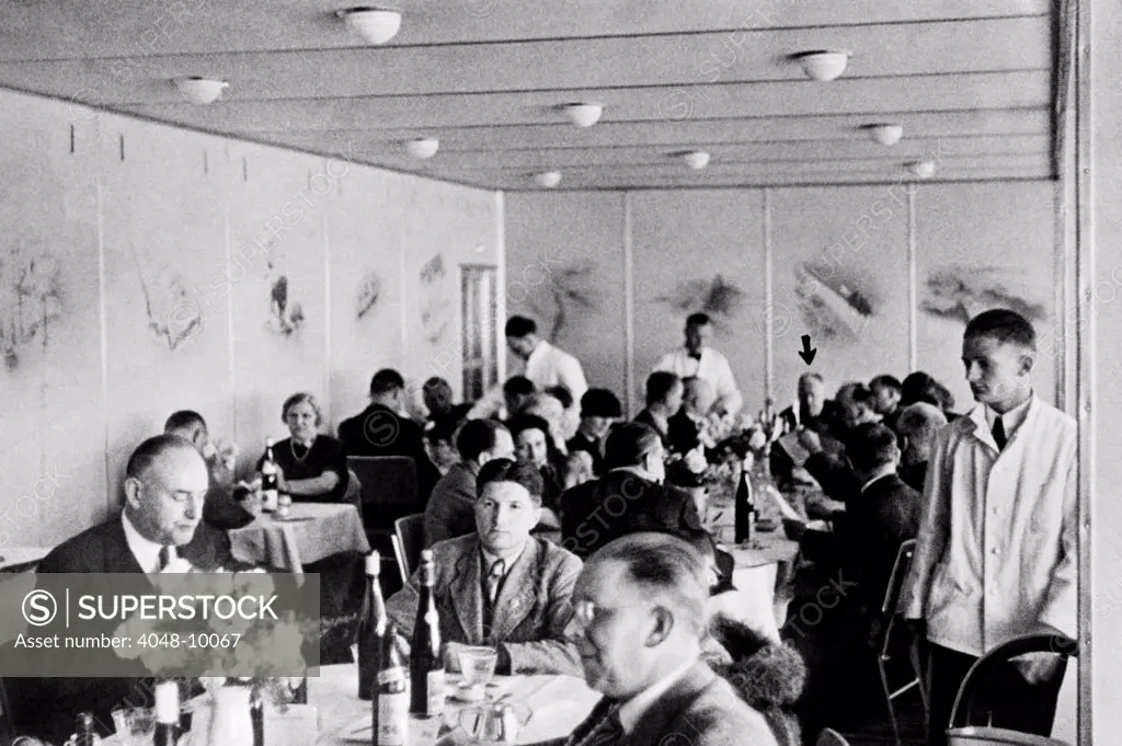 Dining 2,000 feet in the air on the Hindenburg with wine on every table. Dr. Hugo Eckener, the manager of the Luftschiffbau Zeppelin, is at the head of the Long Table. May 10, 1936.
