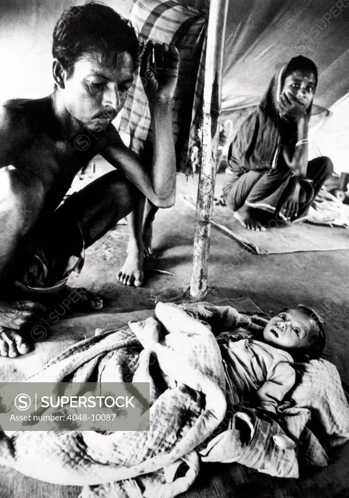 Father's vigil over his dying son in a refugee camp during the Bangladesh Liberation War in 1971. They are part of the 9.5 million who have fled East Pakistan and are vulnerable to hunger and disease. Nov. 1971.