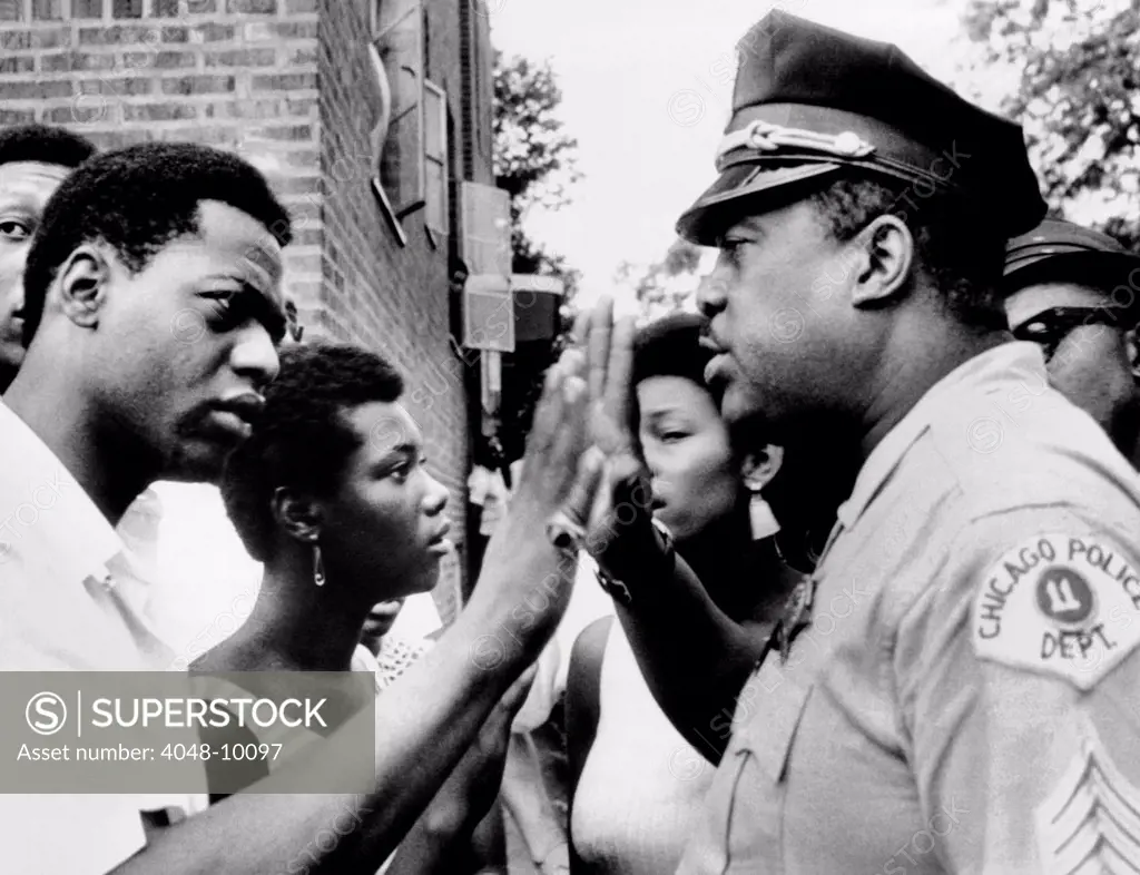 Chicago African American policeman tries to calm a crowd. Violence broke out for the second night in a row on the southwest side. July 13, 1966.