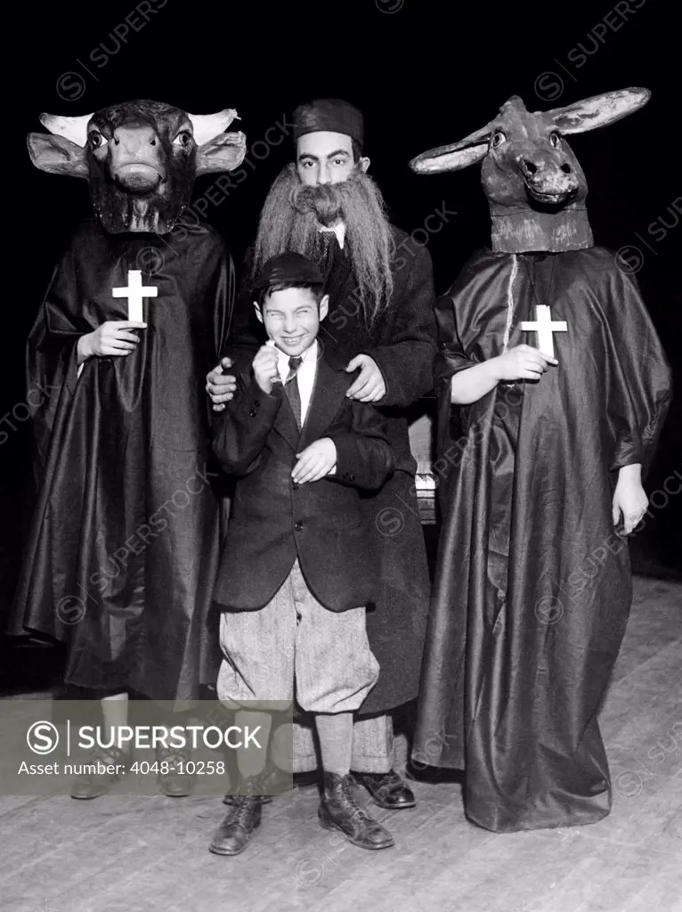 Young Communists stage an anti-religion tableau. Young Pioneers dress in costumes mocking religion. A bearded rabbi is pictured in the center flanked by two nuns with donkey head and a bull head masks. In front is the rabbi's son. The show was on Christmas day, at New York's Central Opera House, in 1930.