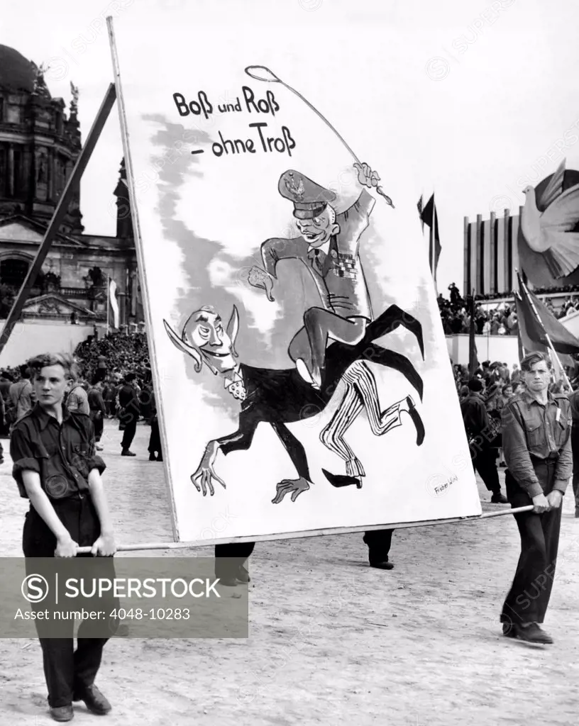Communist Youth organizations put on a 'Peace' parade. A group of teenage boys carry an anti-American sign depicting General Dwight Eisenhower riding on the back of West German chancellor Konrad Adehauer. March 14, 1951.