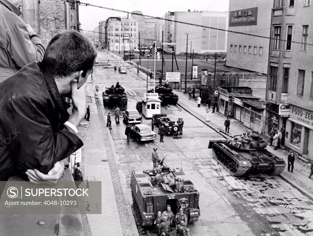 American tanks at the Friedrichstrasse checkpoint crossing through the Berlin Wall. A man looks down from a window at U.S. tanks and troops at Checkpoint Charlie. Oct. 25, 1961.