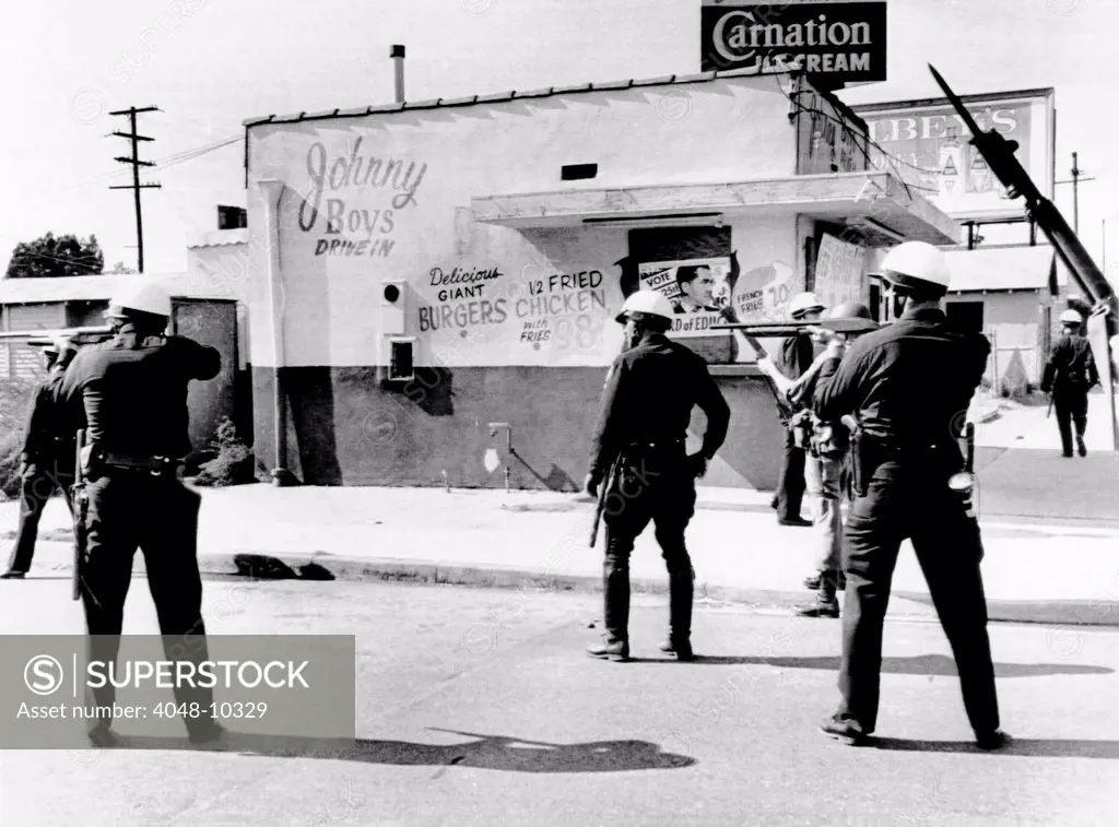 1965 Watts Riot. Police and National Guardsmen hold guns ready as the sweep down San Pedro Street in a major riot torn area in Southeast Los Angeles. August 14, 1965.