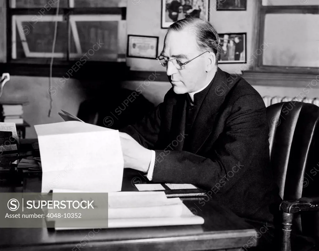 Father Edward J. Flanagan, founder and director of Father Flanagan's Boy's Home at Boys Town, Nebraska, is shown at his desk. Ca. 1935.