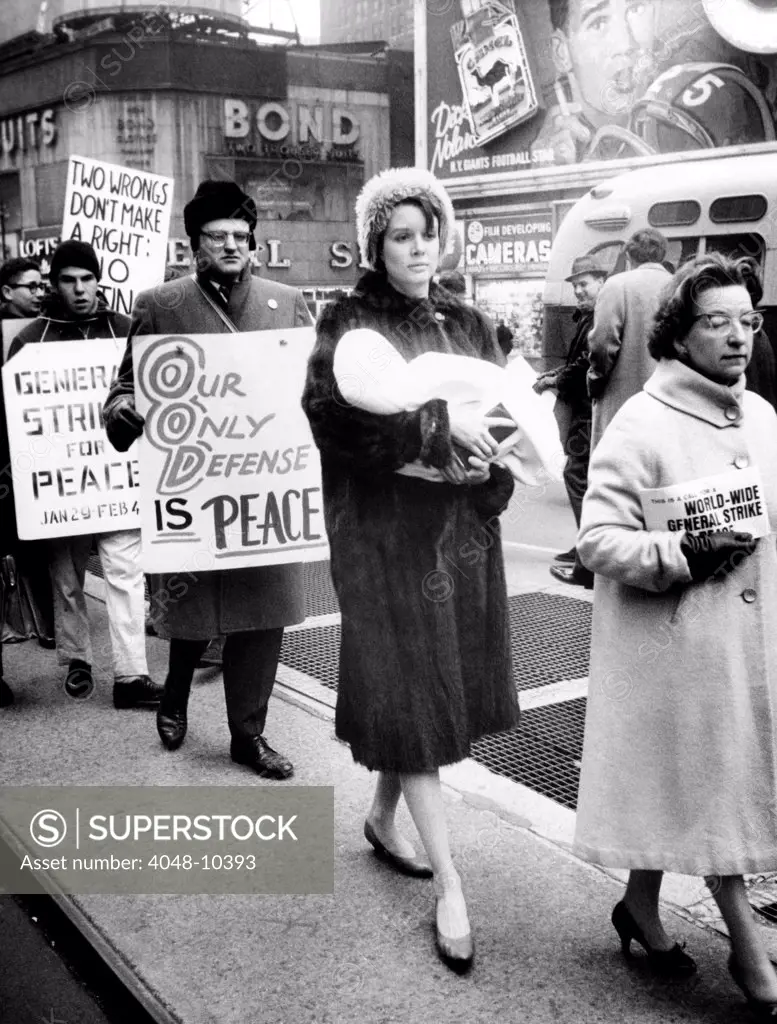 A Mother carries her baby as she participates in a pacifist demonstration. Women's Direct Action, maintained daily vigils at Times Square to end to nuclear testing. Feb. 1, 1962.