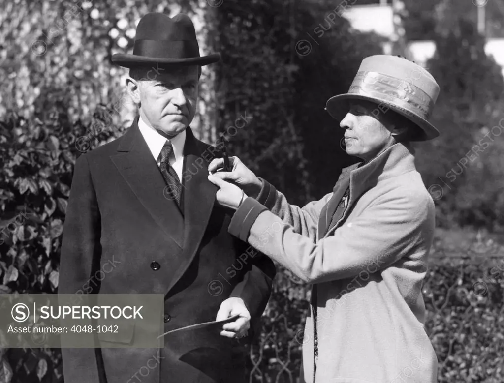 First Lady Grace Coolidge pins a Red Cross button on President Calvin Coolidge's coat, 1925