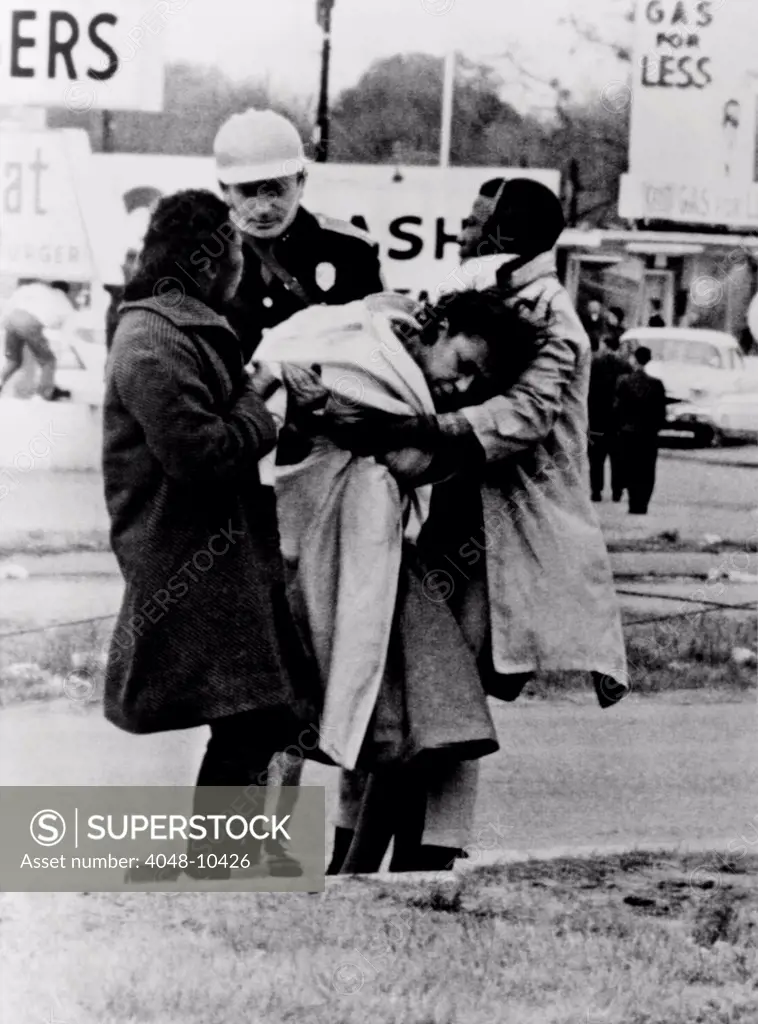 Alabama State Trooper offers no assistance. An unconscious woman is removed by two fellow marchers after she fell in charge of police that broke up first attempted Selma-to-Montgomery on March 7, 1965, afterward called 'Bloody Sunday'.