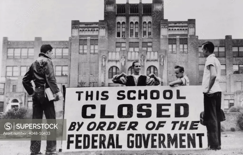 Little Rock Central High was closed to avoid integration. Four students pose with a large sign reading 'This school closed by order of the federal government.' The city government closed the school for the 1958-59 academic year rather than continue racial integration.