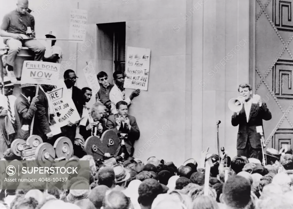 Attorney General Robert Kennedy addresses civil rights demonstrators. He denied that the Justice Department discriminated against Blacks, and hired on the basis of ability and integrity. He added that ' I'm not going to go out and hire a Negro just because he is not White.' June 14, 1963