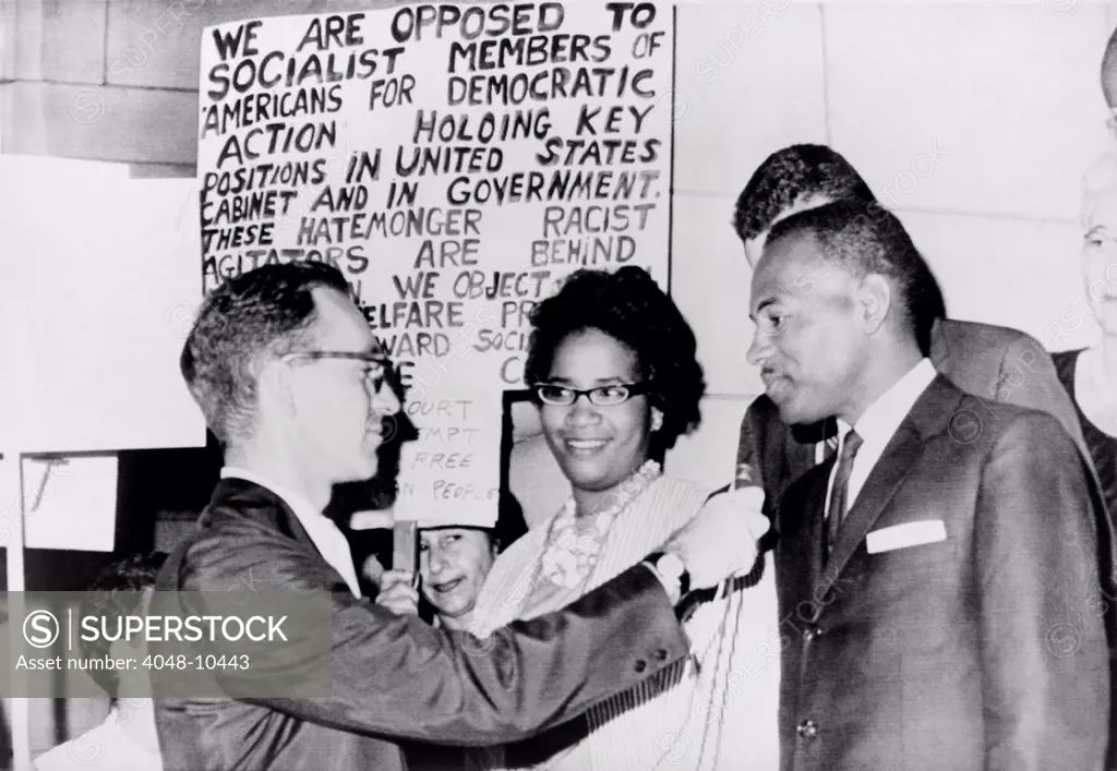 James Meredith and wife in front of segregationist poster as they talk to a reporter. The Fifth U.S. Circuit Court of Appeals ordered his admission to the University of Mississippi. Sept. 25, 1962.