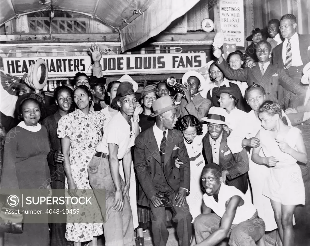 Joe Louis fans in front of fan headquarters to celebrate Louis' close decision victory over Tom Farr, the famous Welsh/British boxer. Harlem, New York City, August 30, 1937.