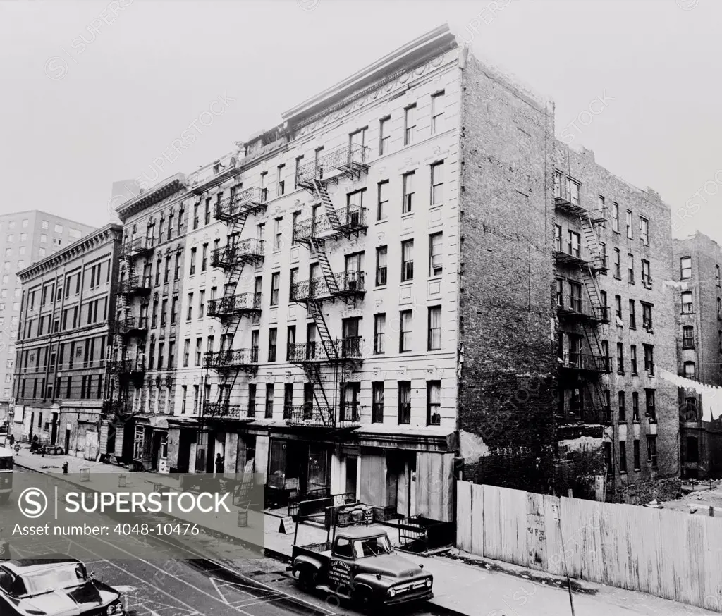 East Harlem street and large tenement apartment building at 311 East 100th Street in New York City. 1964.