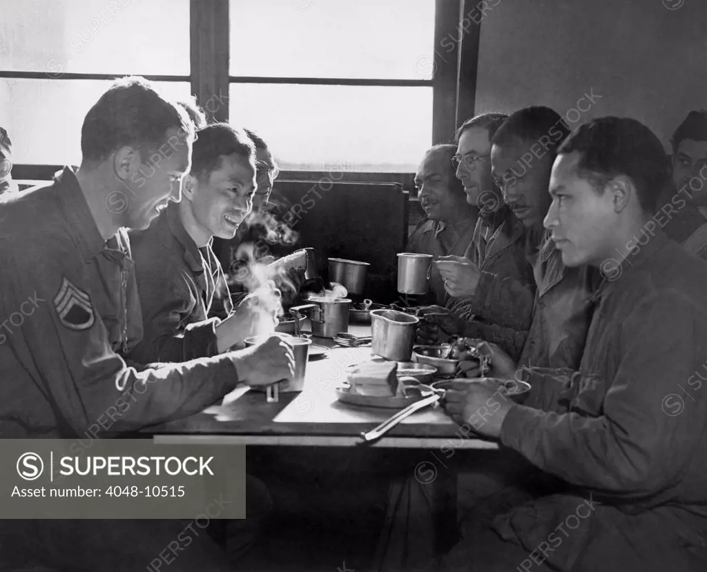 African American, Chinese, Puerto Rican, and White US soldiers eating together in a mess hall. They are all serving at the Army Quartermaster Supply Depot in England. 1944.