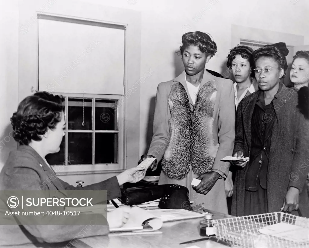 African American women presenting papers to a WAC, as they register for basic training in the Women's Army Corp during World War II. Ca. 1943-45.