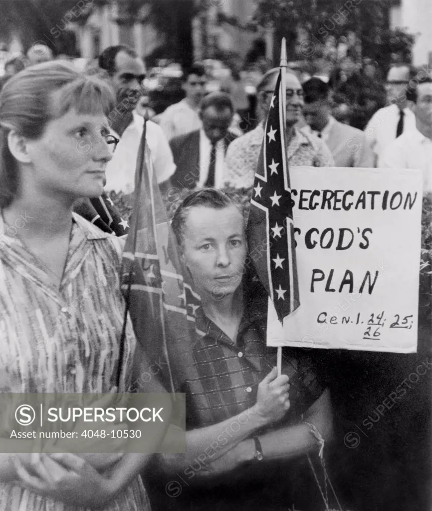 St. Petersberg, Florida demonstrators support segregation. Woman holds a Confederate flag and a sign reading, 'Segregation is God's Will'. 1960s.