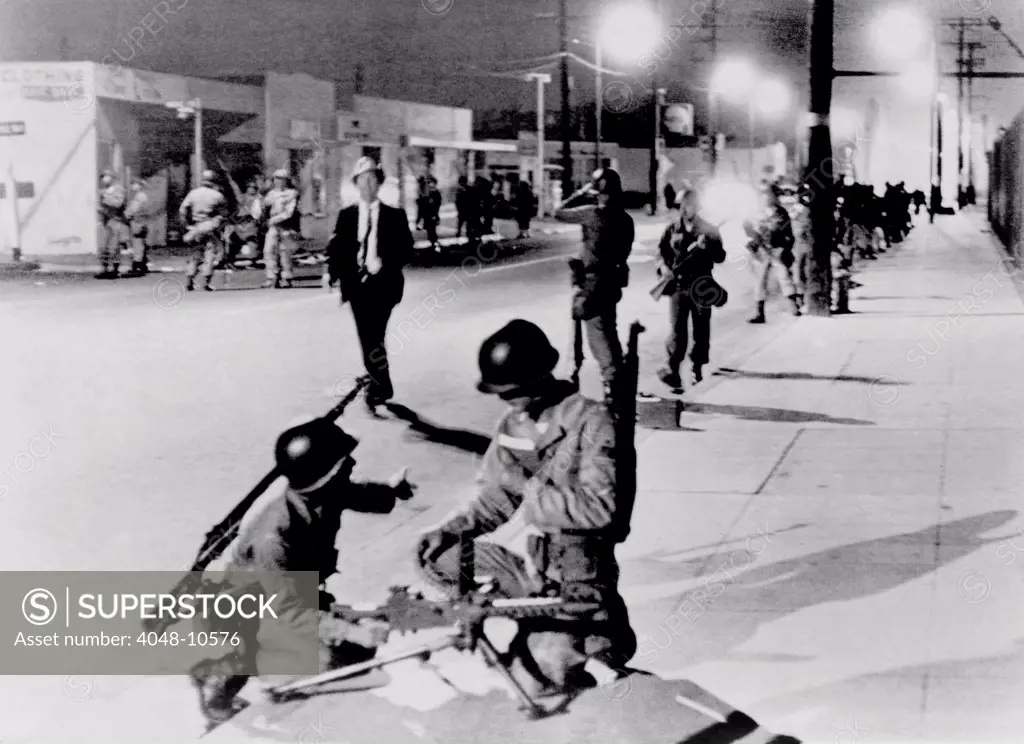 California National Guardsmen take up positions a street in the Watts section of Los Angeles during race riots. Aug. 14, 1965.