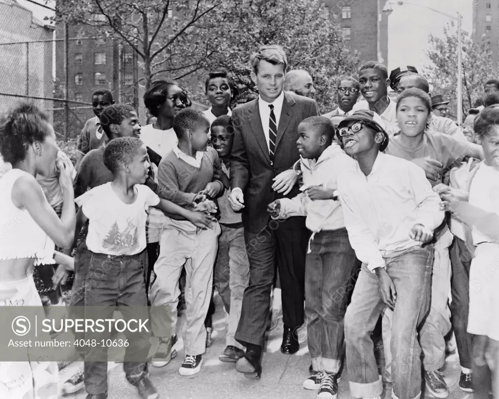 Attorney General Robert Kennedy surrounded by African American children. He was visiting a summer reading program in Harlem at the Morningside Community Center, in Manhattan. Aug. 14, 1963.